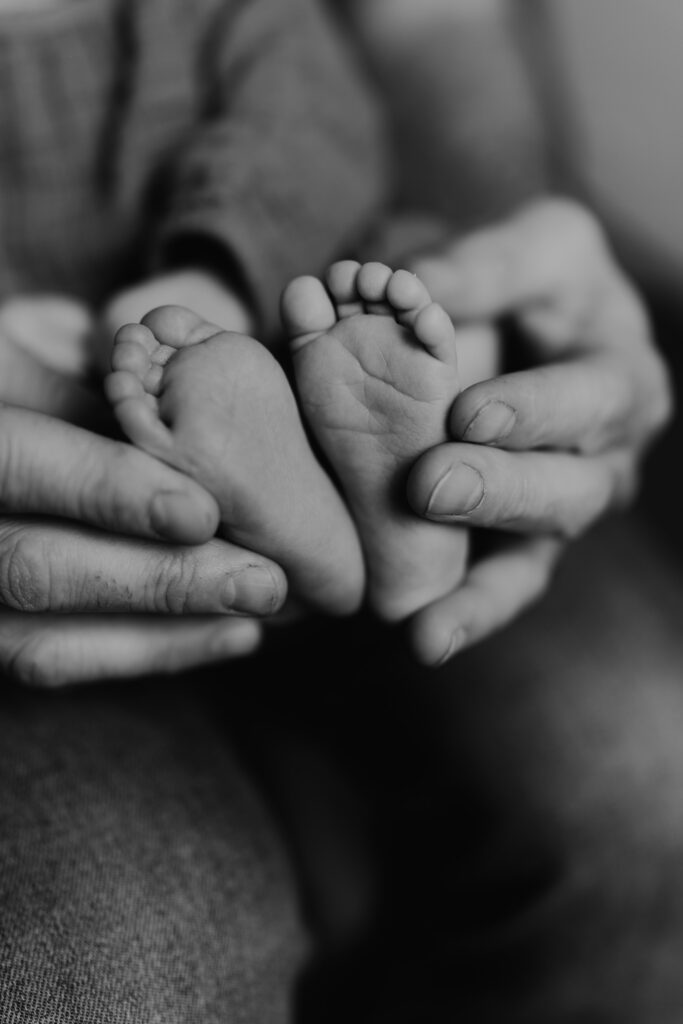 Photographe à Limoges -Photo noir et blanc de petit pied d'un bébé dans les mains de ses parents